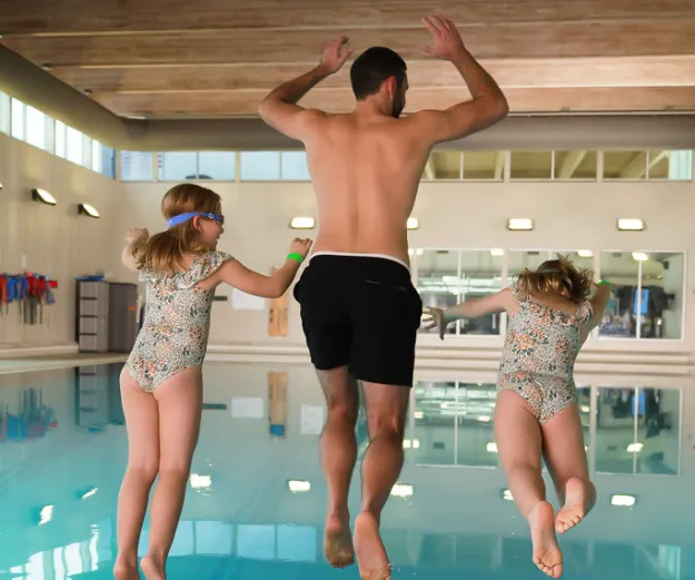 Dad and kids jump in YMCA swimming pool