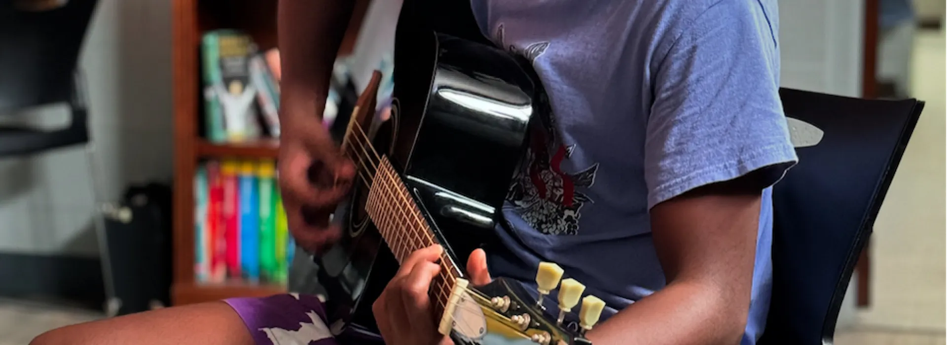 child sitting down playing the guitar